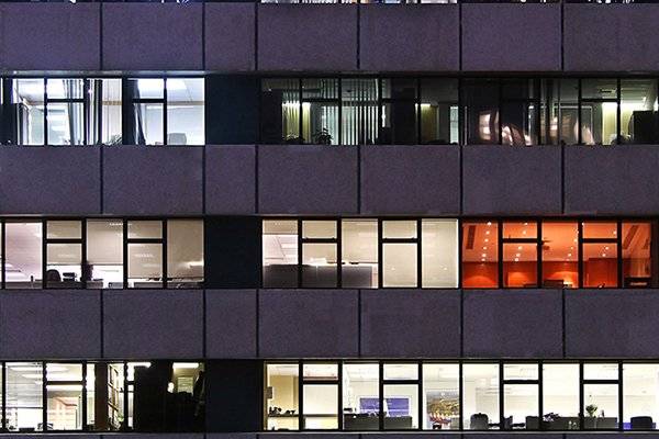 En erhvervsbygning ses om aftenen, hvor der er lys på de forskellige etager.